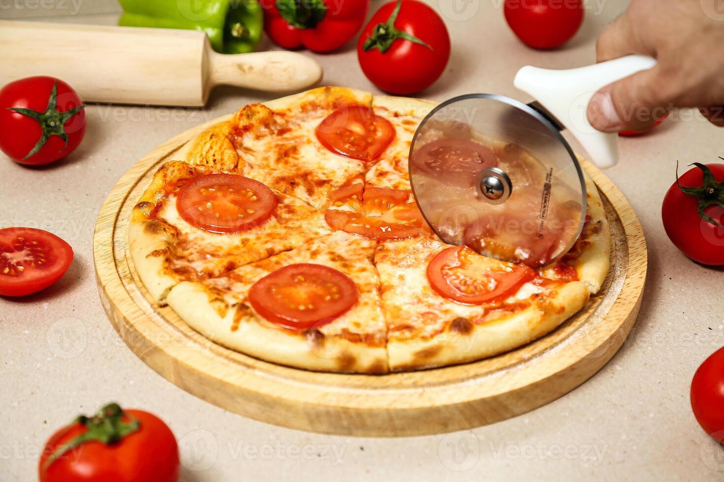 Person Cutting Pizza With Pizza Cutter photo