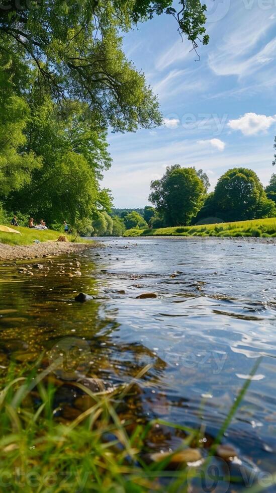 Riverside Picnic, a peaceful riverside scene with people having a summer picnic photo