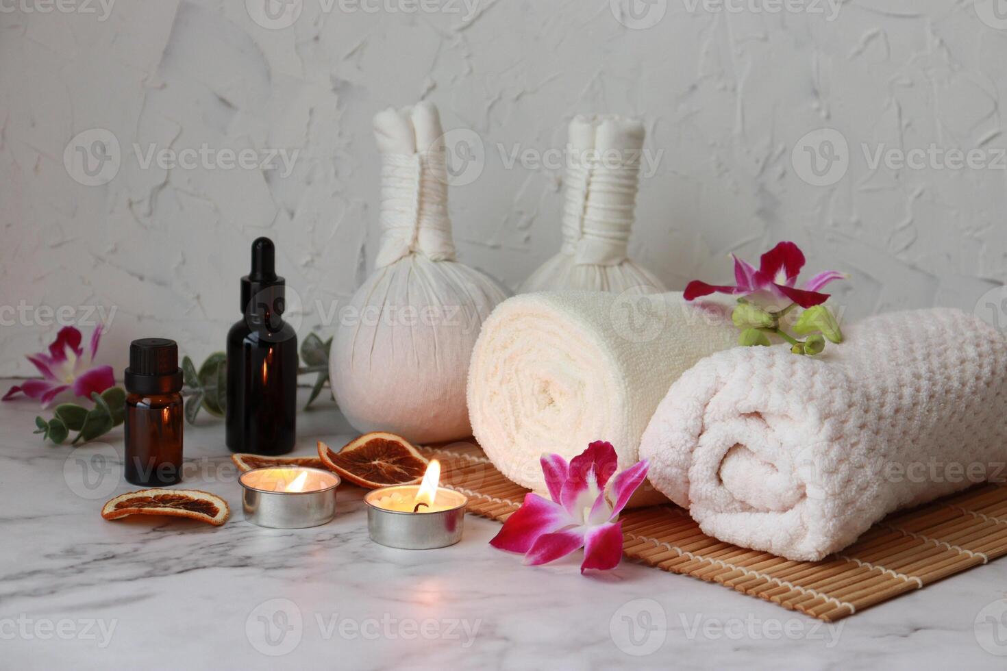 Spa and wellness. Towel, aroma candle, herbal compress balls and essential oil on white background photo