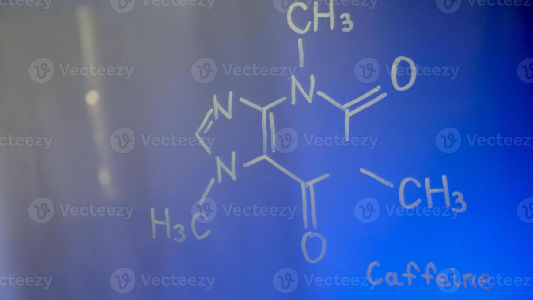 Chemical structure, formula of caffeine on glass in the lab close-up. Lecture on chemistry. Blue background photo