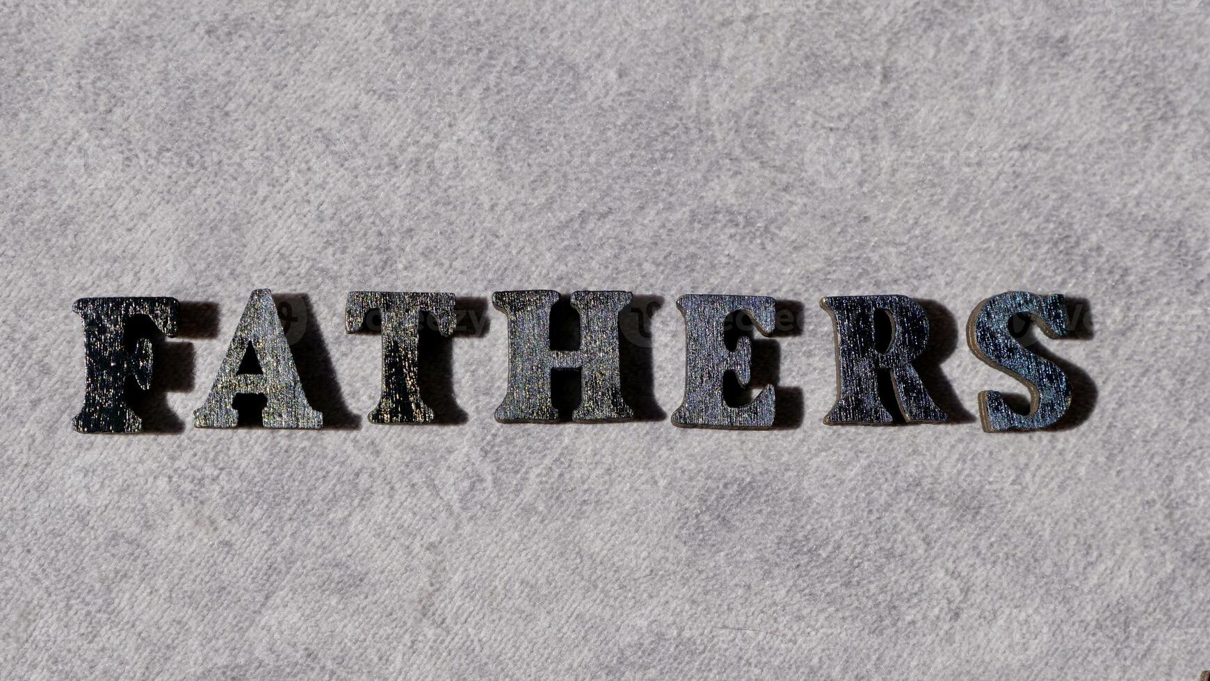 Lettering father in black letters on grey background on father's day close-up photo