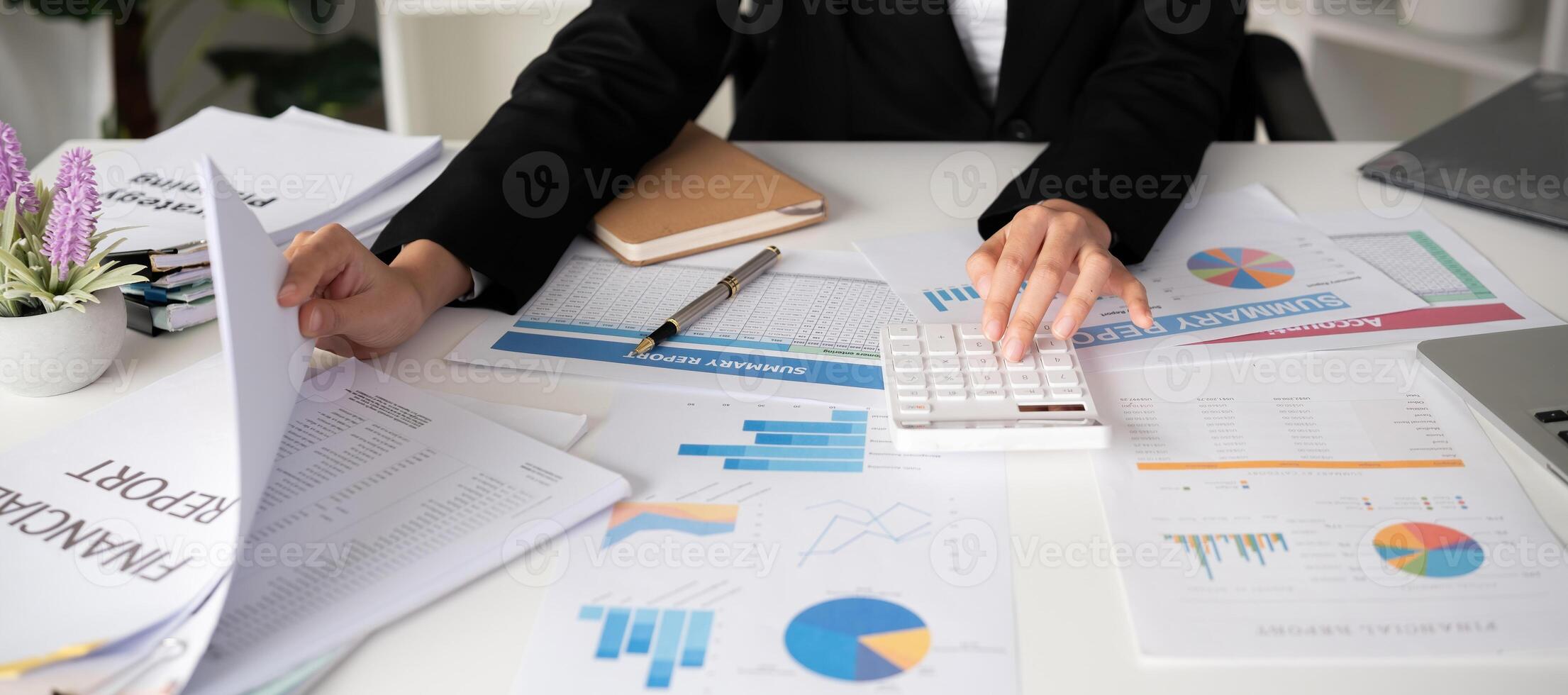 Asian female accountant Use a calculator to calculate business numbers on a white wooden table in the office. photo