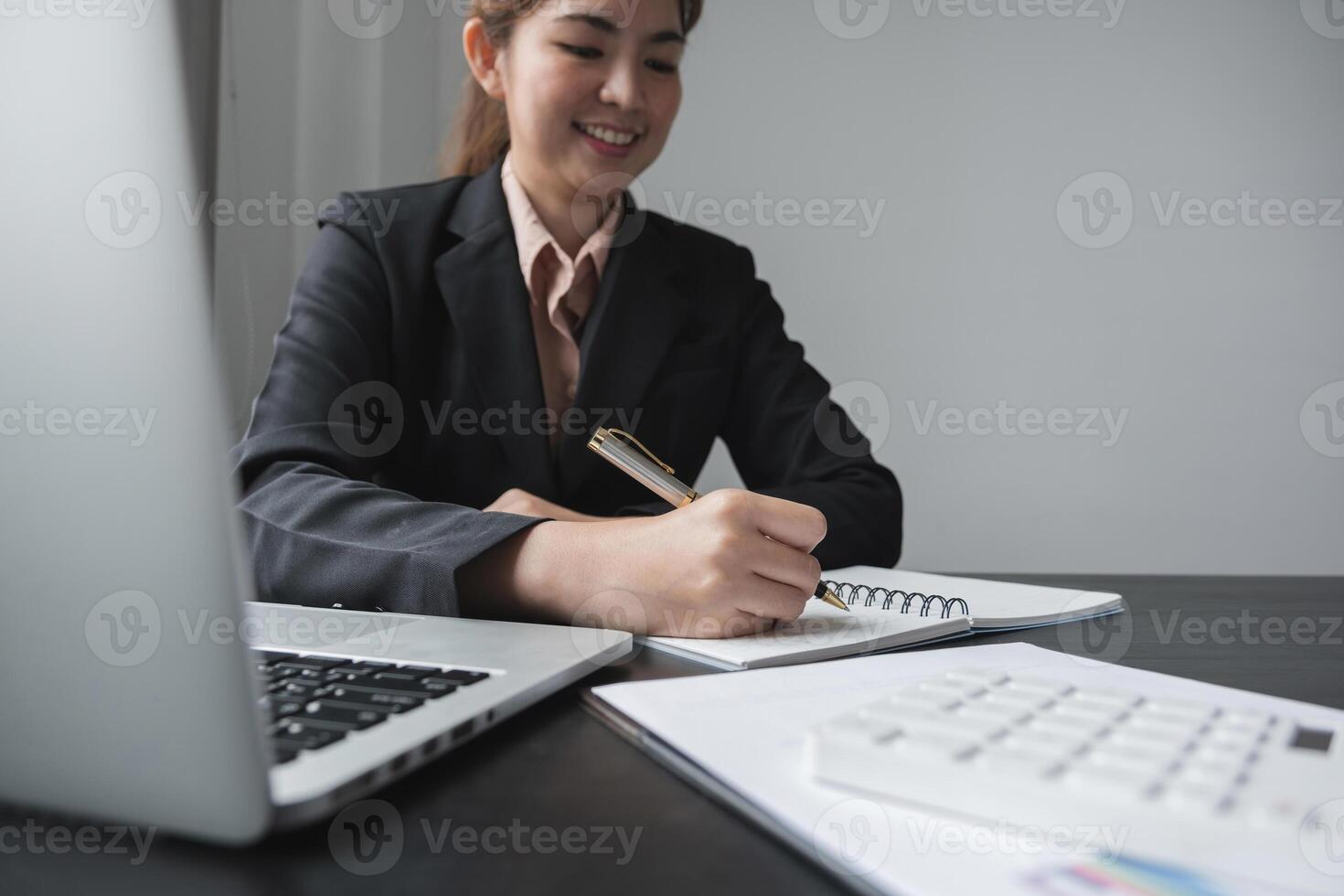 businesswoman writing making list taking notes in notepad working or learning online with laptop at office photo