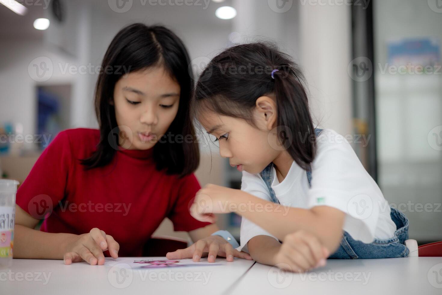 Two young girls are sitting at a table photo