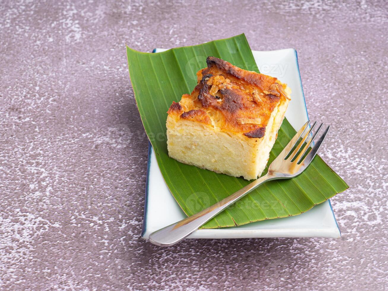 Thai custard cake on banana leaf and spoon on white plate with stone background photo