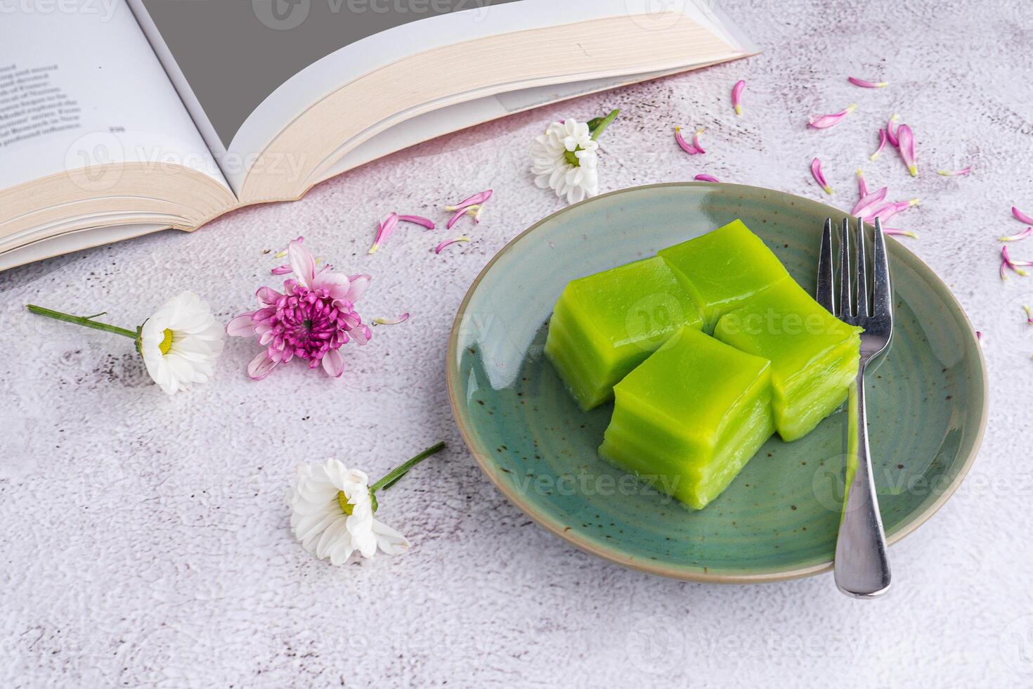 Layer sweet cake on a plate and a cup of white coffee with a book on gray stone background photo