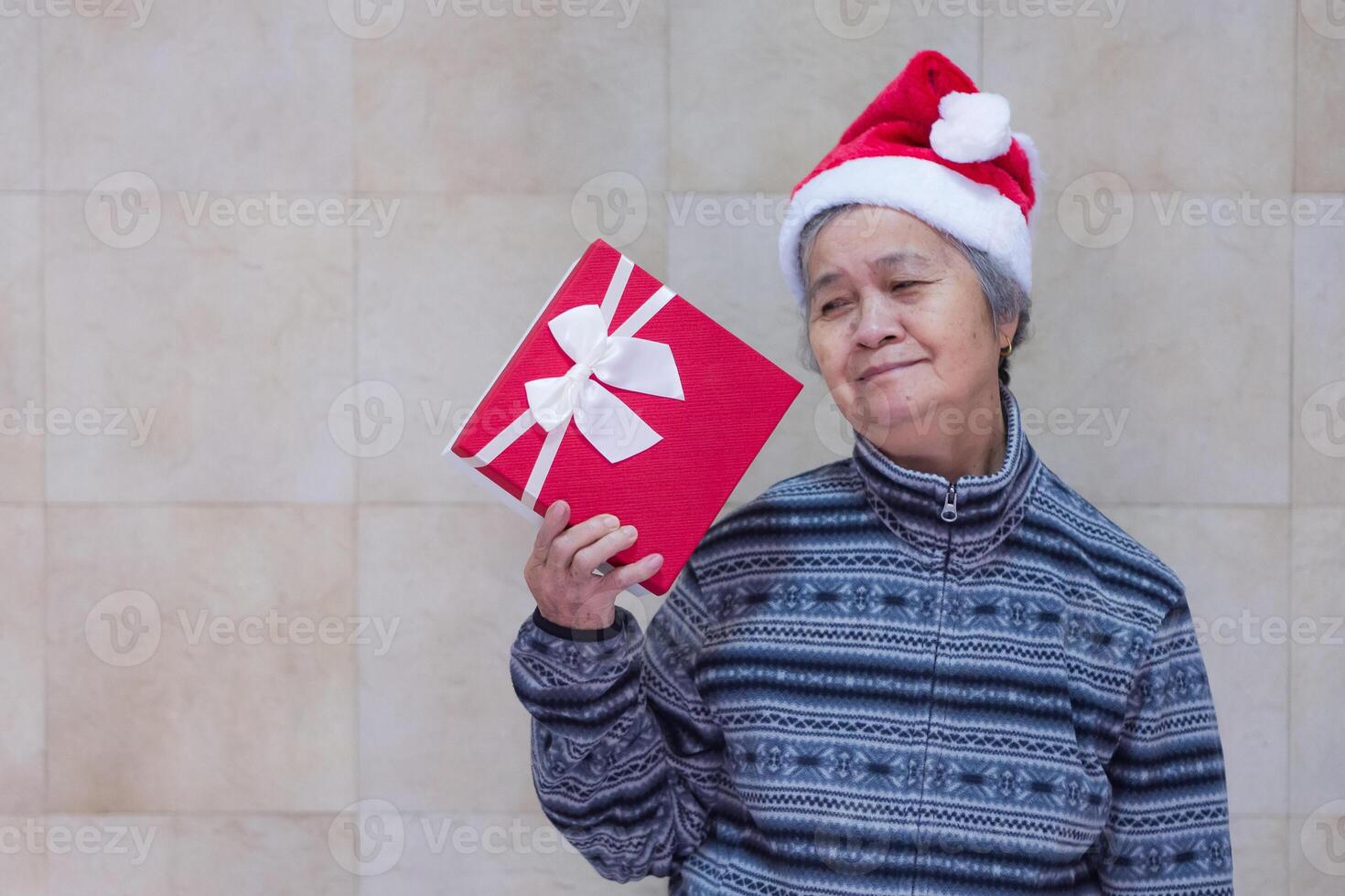 Senior woman holding and looking at a gift box while standing in the home photo