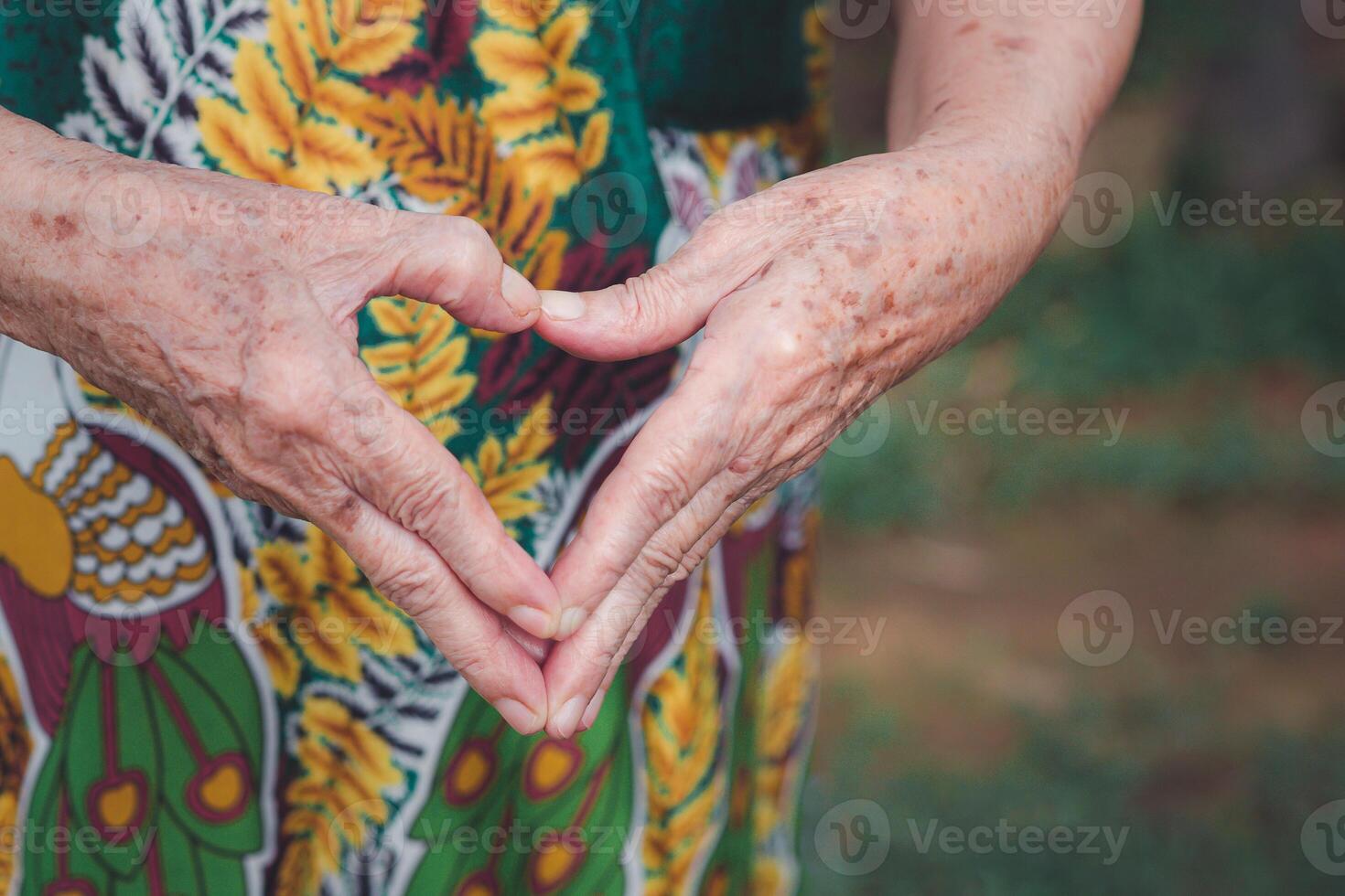 Close-up of hands senior woman showing heart figure with fingers photo