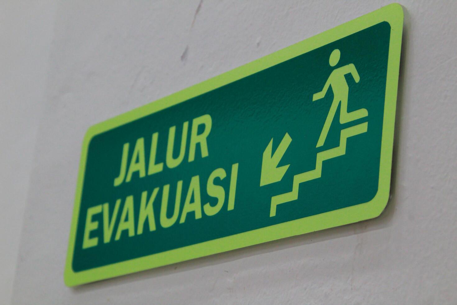 Matram, Indonesia, 13 June 2024. Evacuation route sign with white Wall background photo