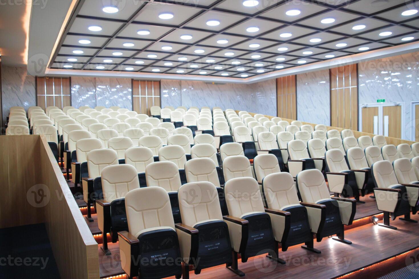 Rows of cream-colored chairs in an empty auditorium photo