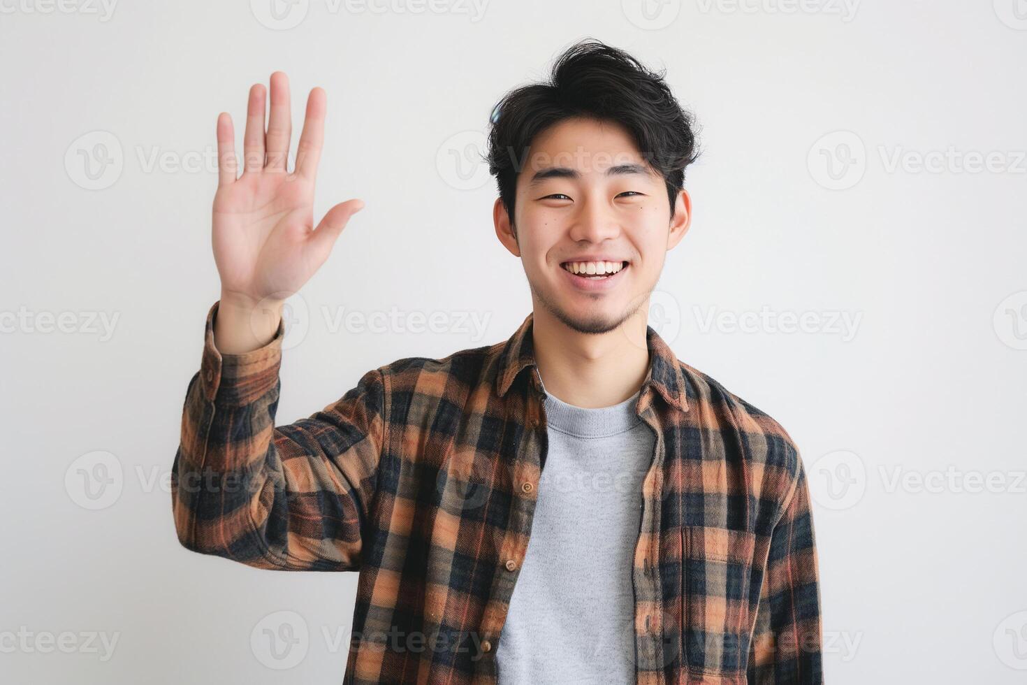 Friendly Asian Man Smiling and Waving Hand Wearing Checkered Shirt in Studio Portrait photo