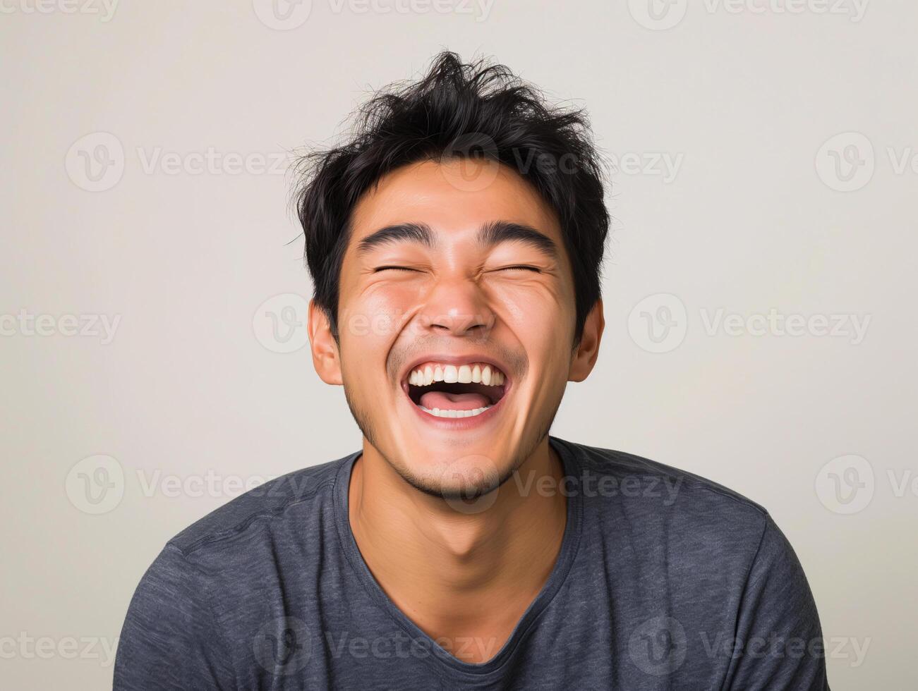 Young Asian Man Laughing Joyfully, Showing Happiness and Positive Emotion, in Casual Gray T-shirt photo