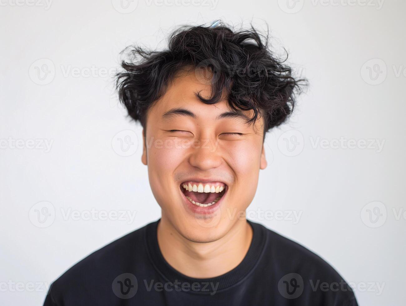 Happy Young Asian Man with Curly Hair Laughing, Displaying Positive Emotion in Casual Black Shirt photo