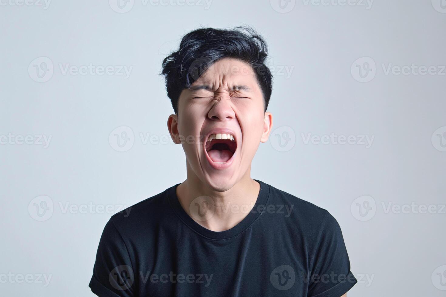 Young Asian Man Screaming in Frustration Wearing Black T-shirt in Studio photo