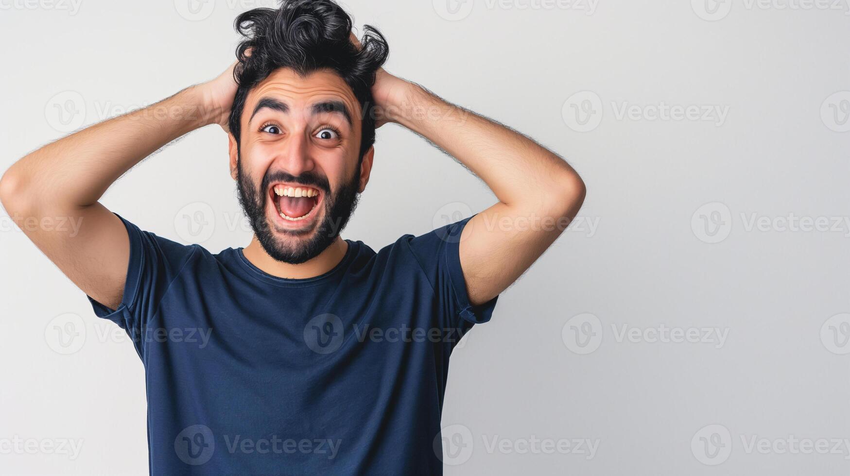 Excited Young Hispanic Man with Beard Holding Head in Surprise and Joy photo