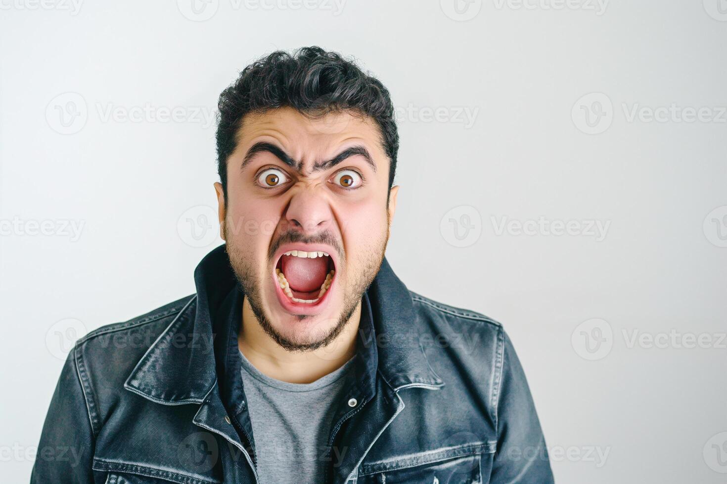 Furious Middle Eastern Man Yelling with Open Mouth in Denim Jacket, Expressing Intense Anger Indoor photo