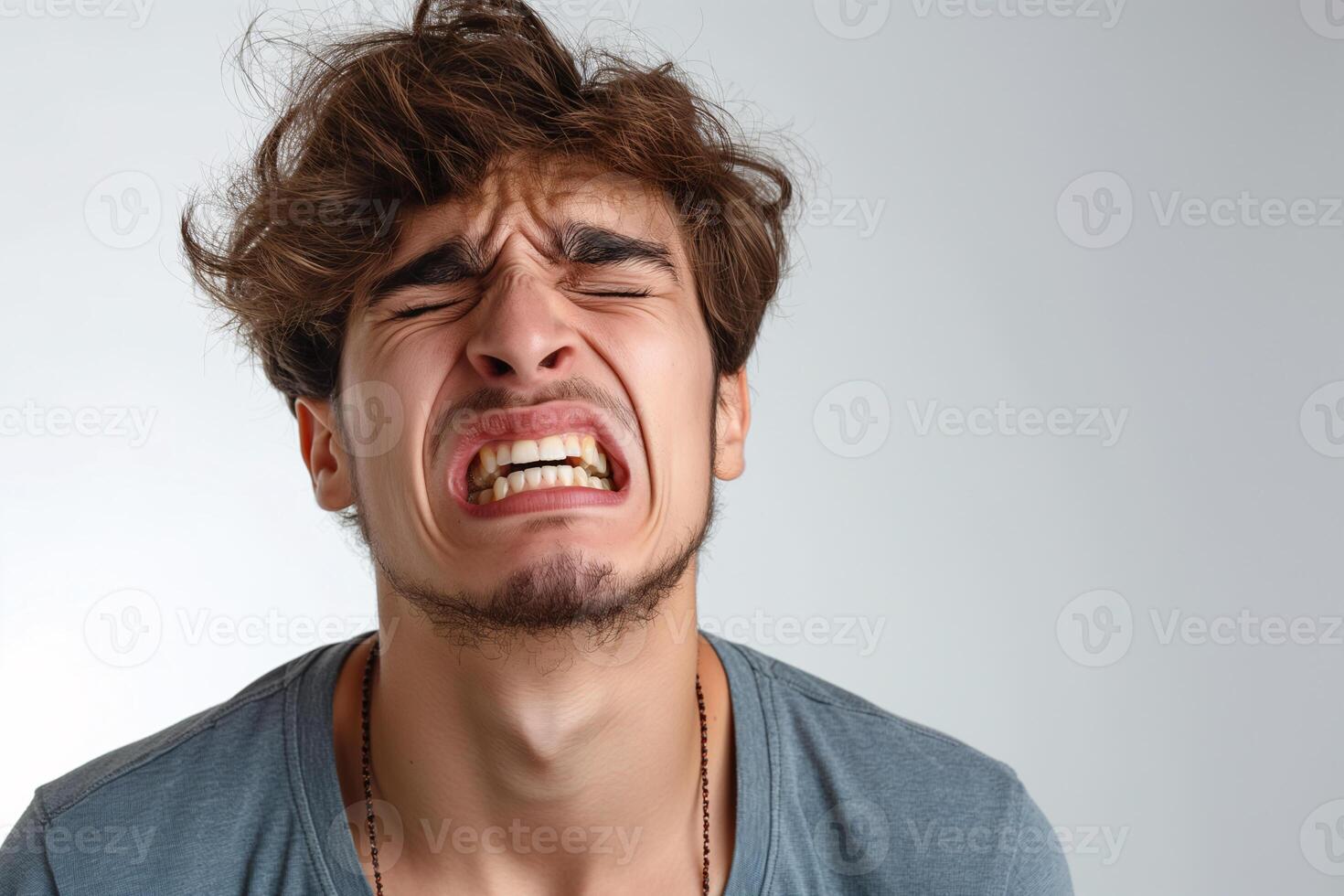 Young Man with Intense Facial Expression in Casual Outfit on Grey Background photo