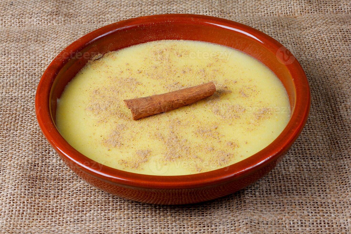 Curau, cream of corn sweet and dessert typical of the Brazilian cuisine, placed in ceramic bowl on wooden table. photo