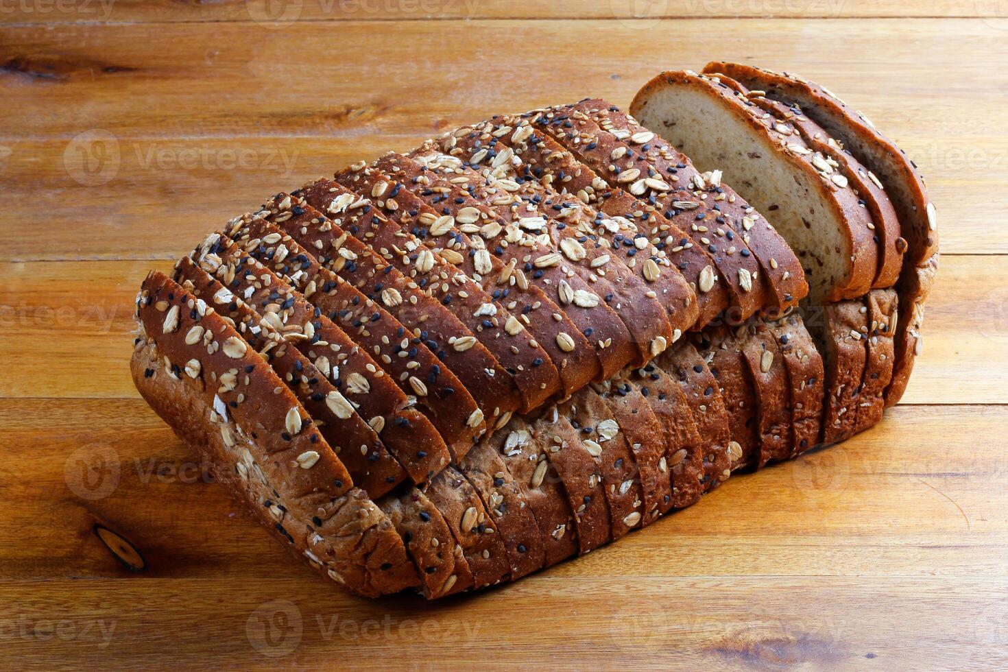 Wholemeal wheat bread or integral bread with grains and seeds sliced on wooden table photo