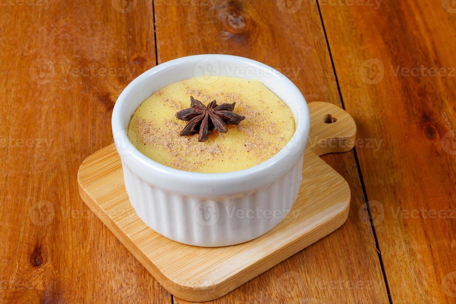 Curau, cream of corn sweet and dessert typical of the Brazilian cuisine, placed in ceramic bowl on wooden table. photo