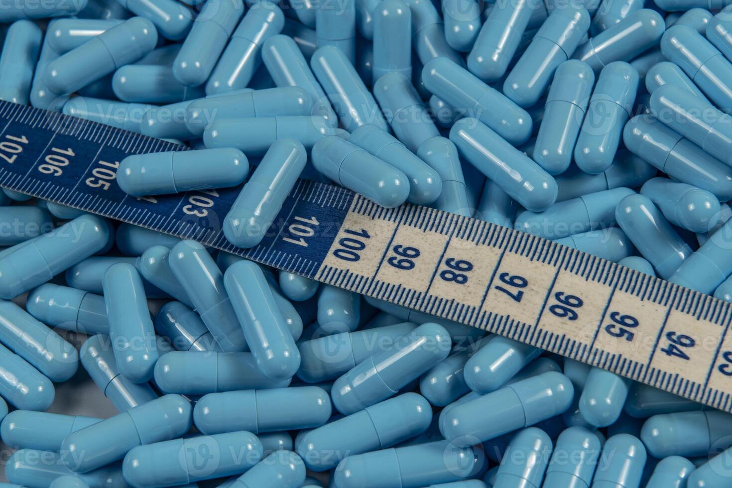 Blue weight loss pills and measuring tape symbolizing slimming photo