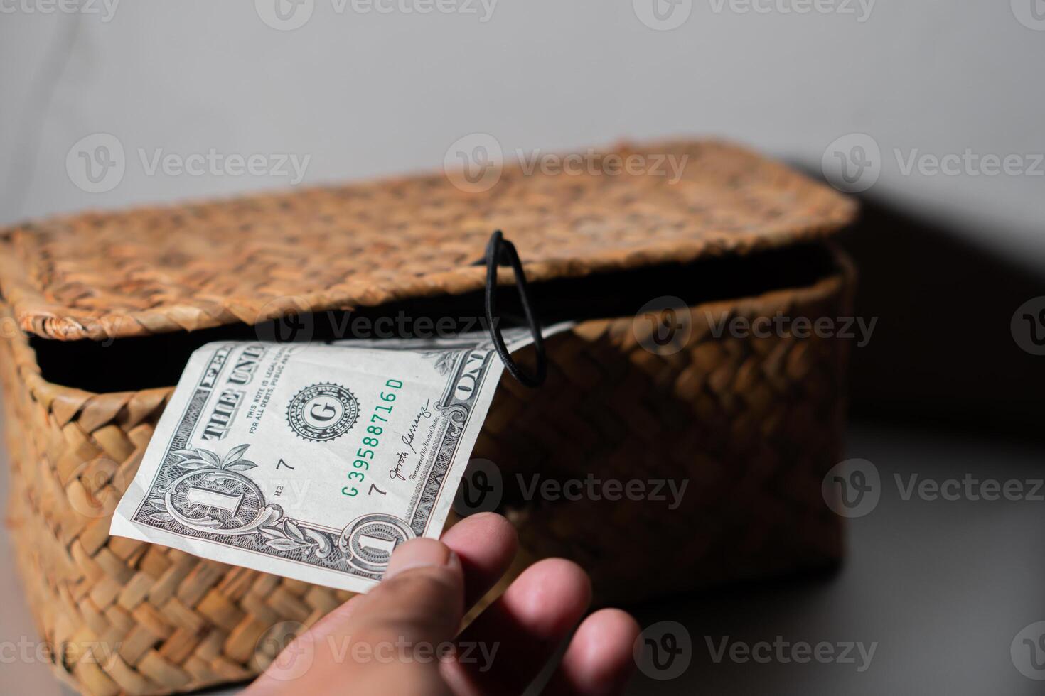 Hand placing dollar bill into woven basket photo