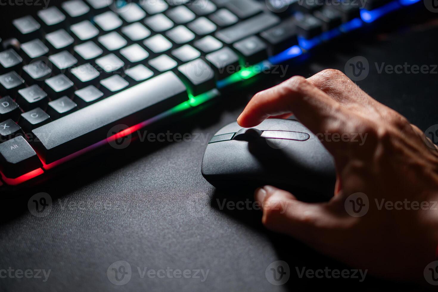 Person using computer mouse with colorful backlit keyboard photo
