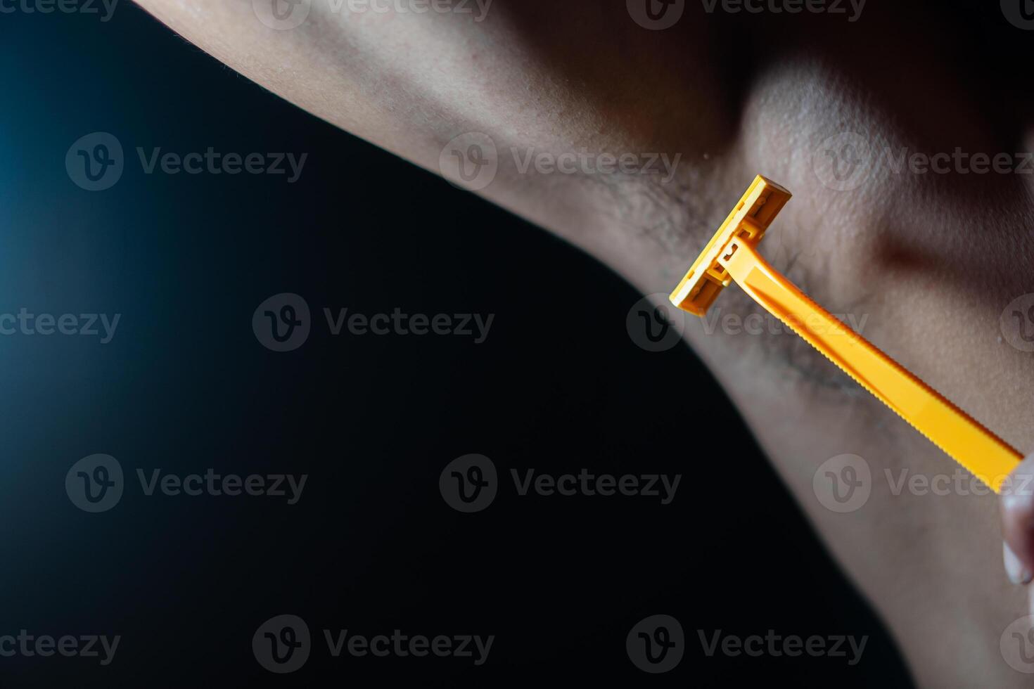 Shaving armpit with yellow razor photo