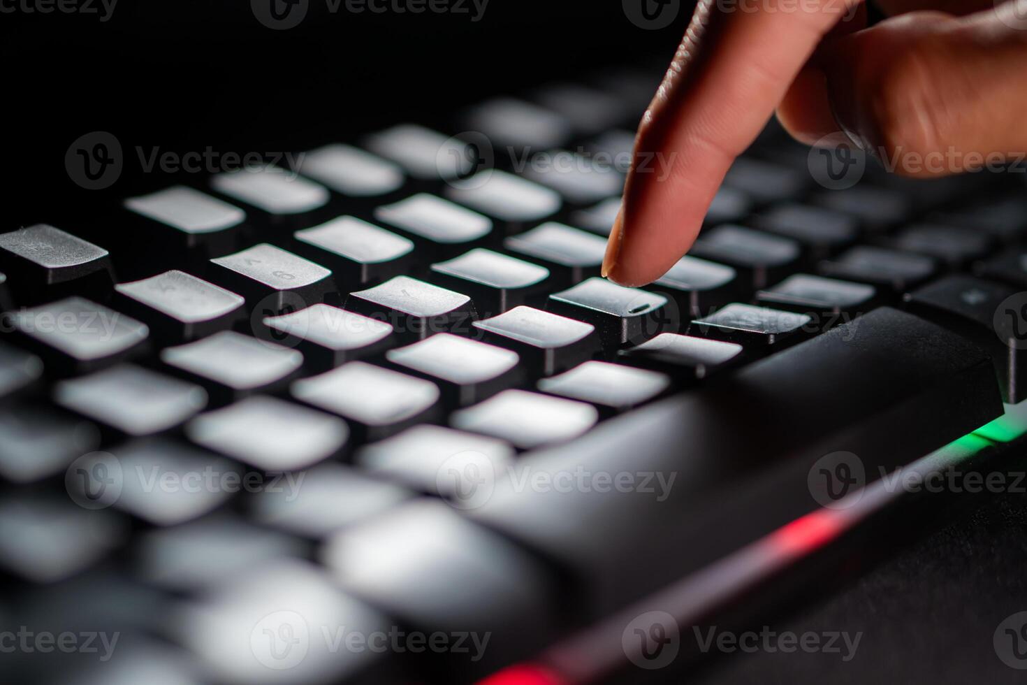Finger pressing key on backlit keyboard photo