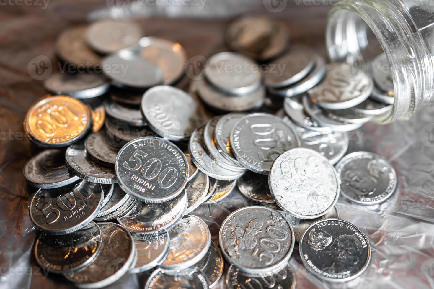 Indonesian 500 Rupiah coins spilling from a glass jar photo