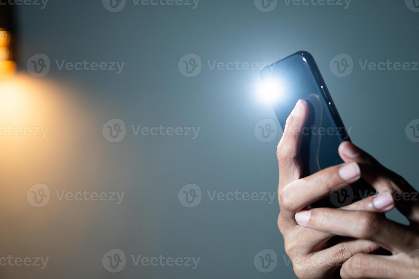 Hand holding smart phone with flashlight on photo