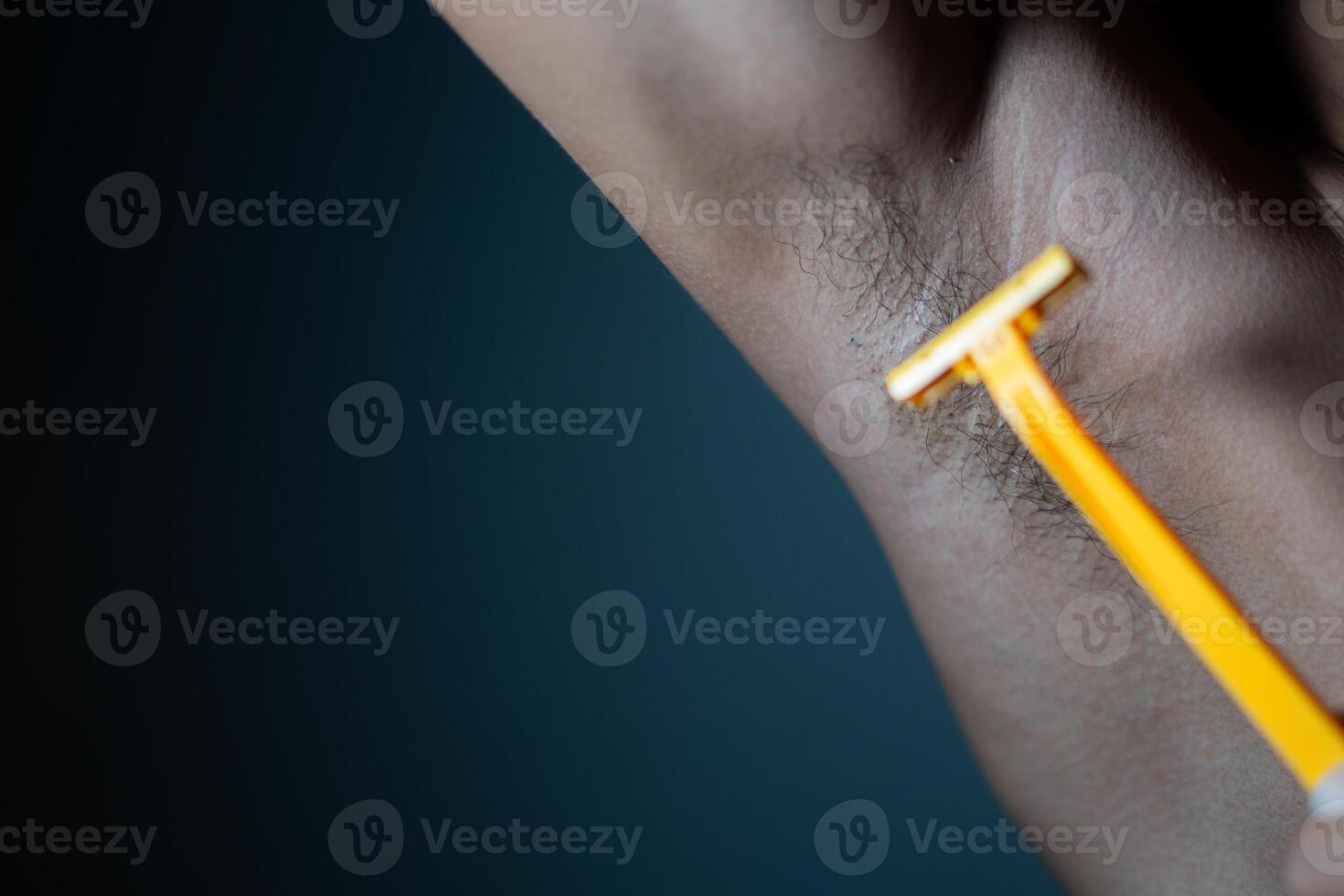 Armpit shaving with yellow razor photo