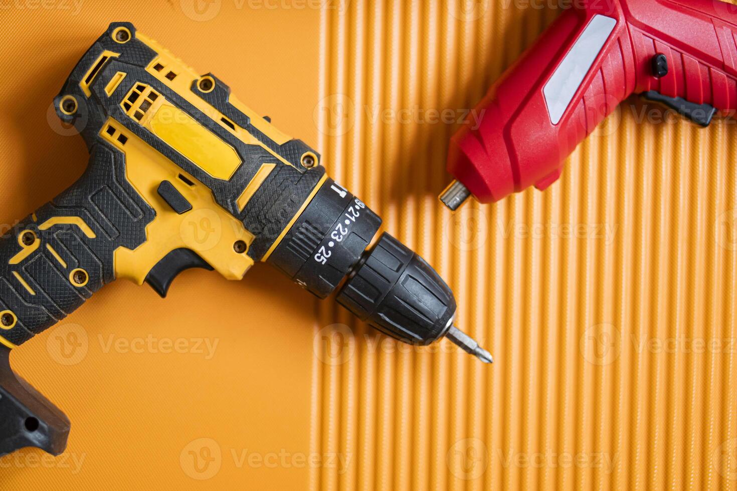 Cordless drill and screwdriver on orange surface photo