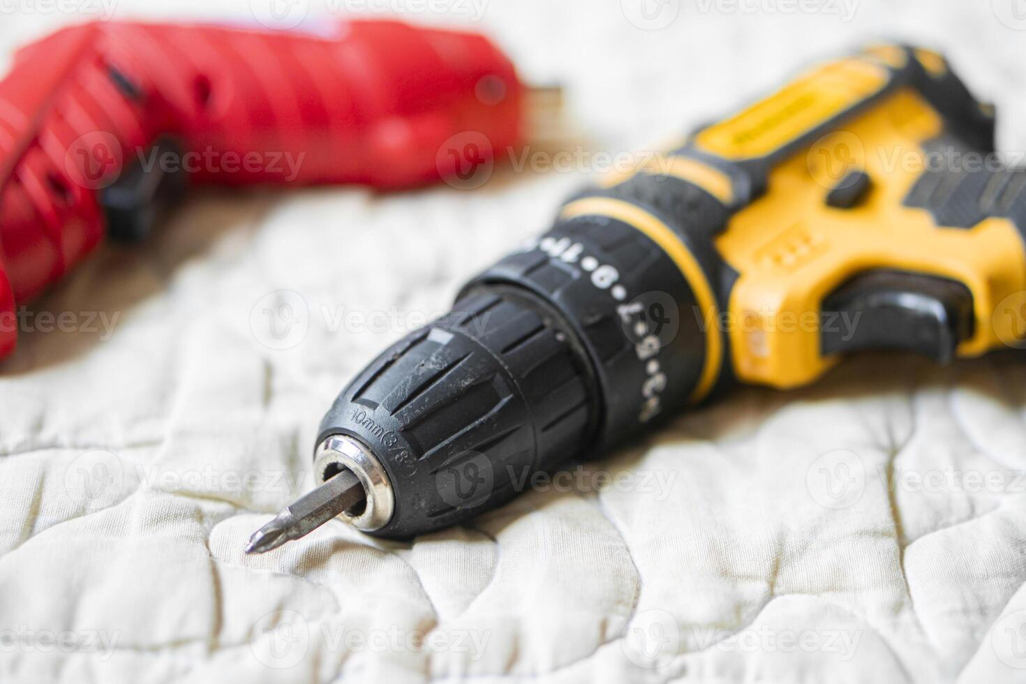 Cordless power drill with screwdriver bit on quilted surface photo