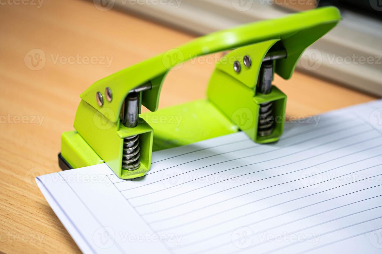 Green two-hole paper puncher on lined paper photo