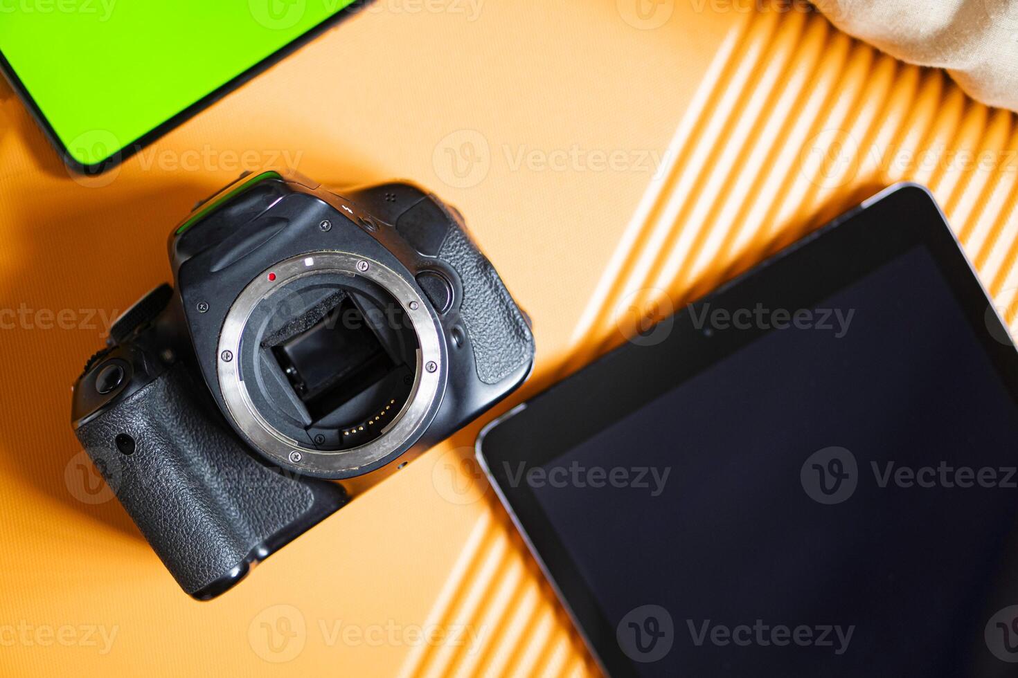SLR camera and tablet on orange surface photo