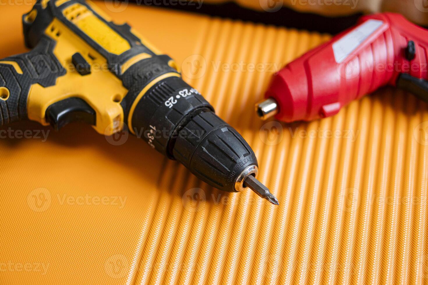 Cordless drill and screwdriver on orange surface photo