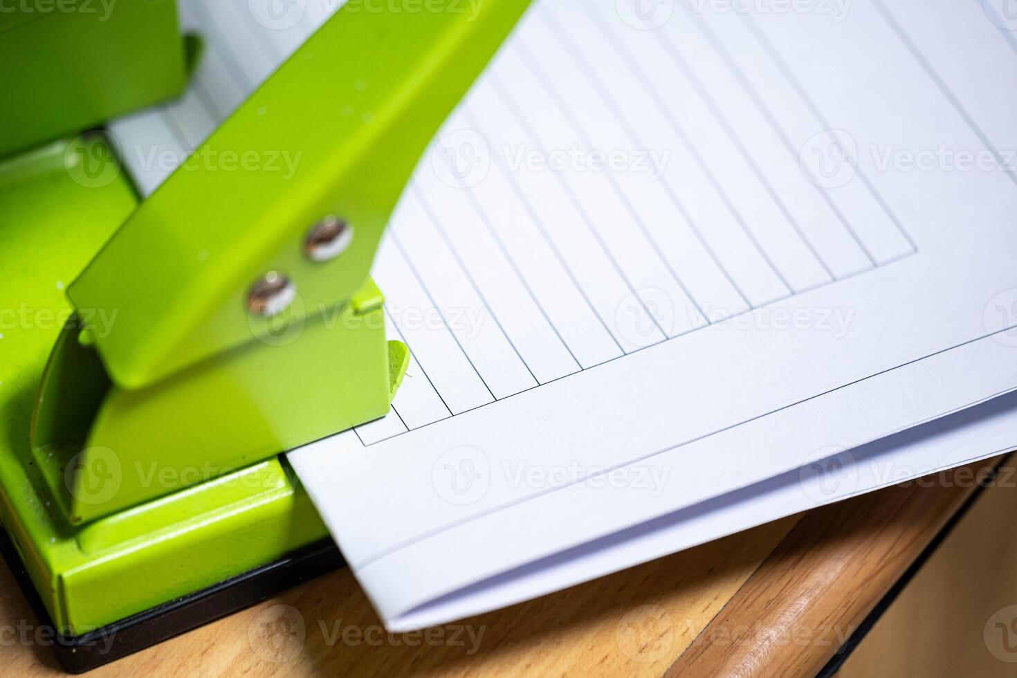 Green hole puncher with lined paper photo