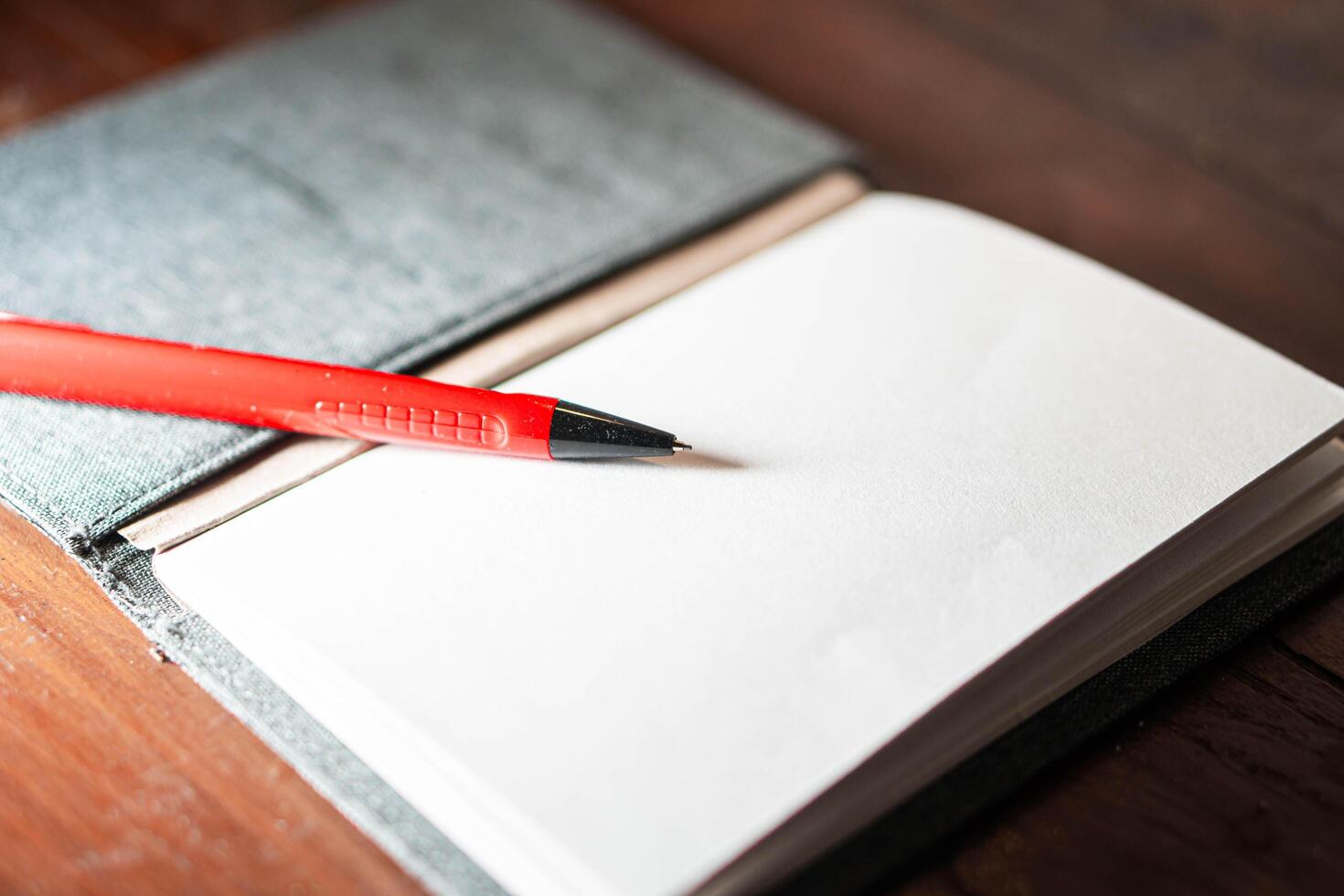 Open notebook with red pen on wooden surface photo