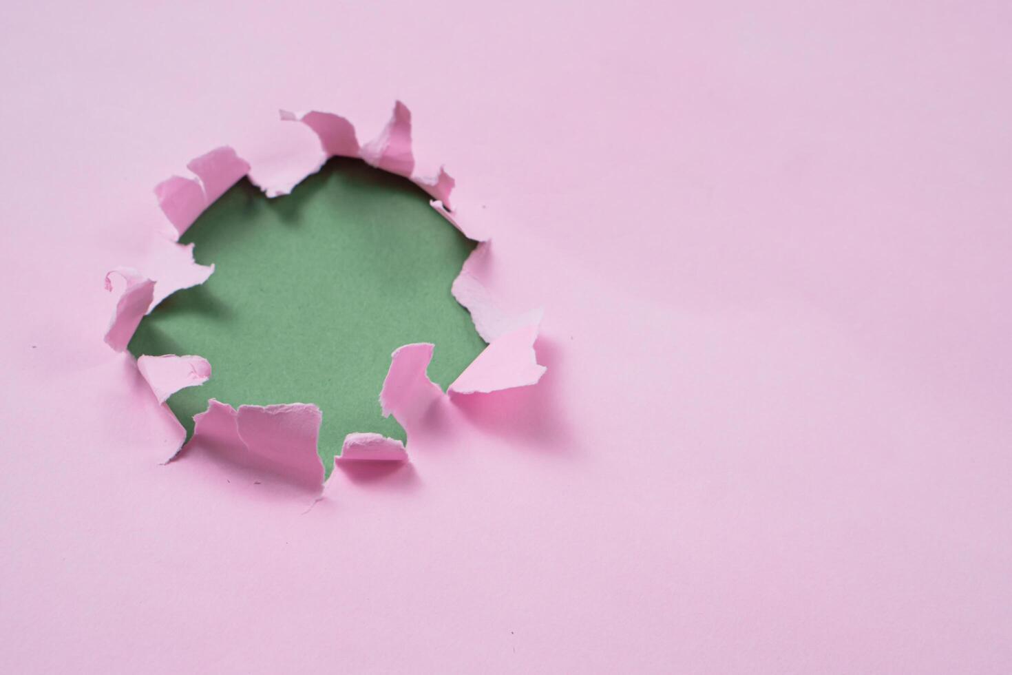 Ripped or torn pink paper frame with green copy space photo
