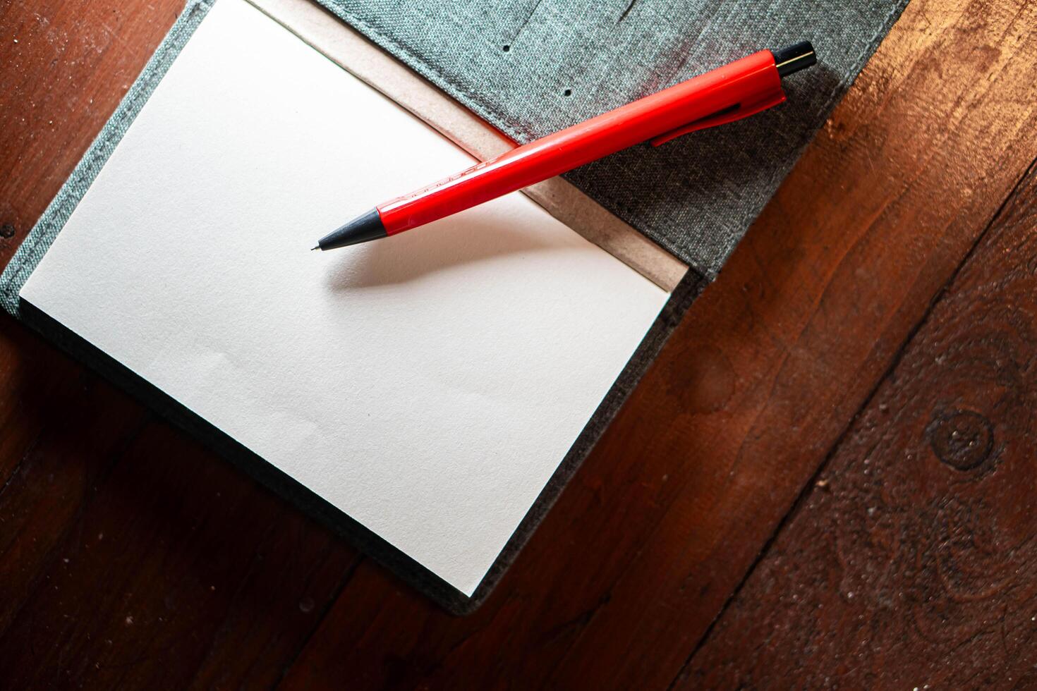Open notebook with red pen on wooden surface photo