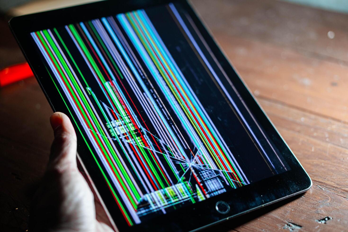 Tablet with broken screen displaying colorful lines photo