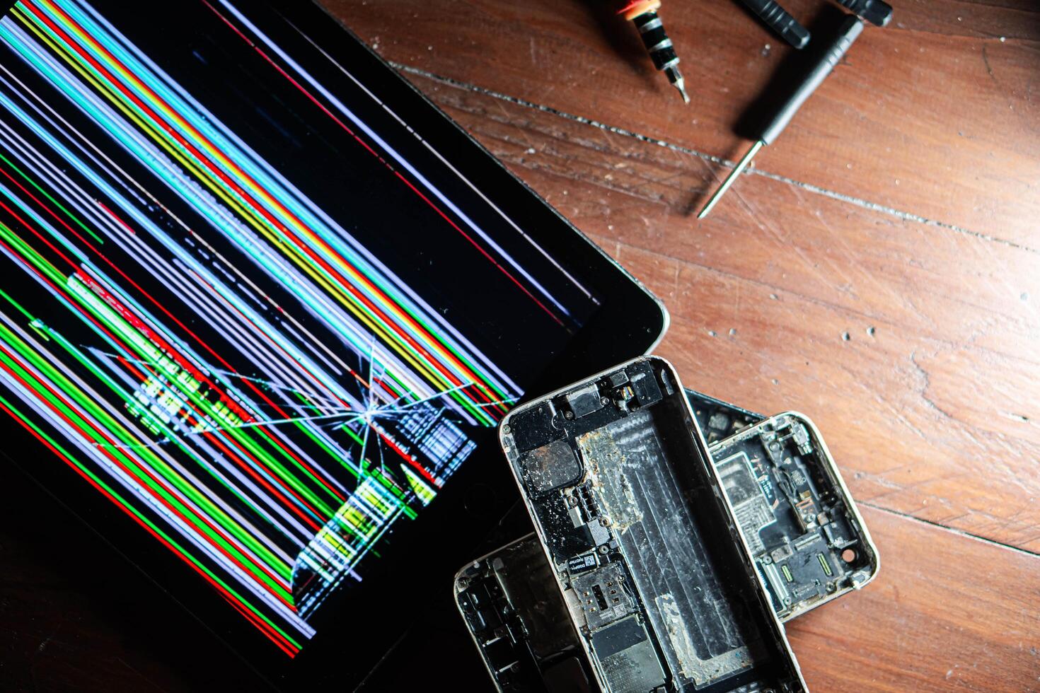 Broken tablet and disassembled smartphones with repair tools photo