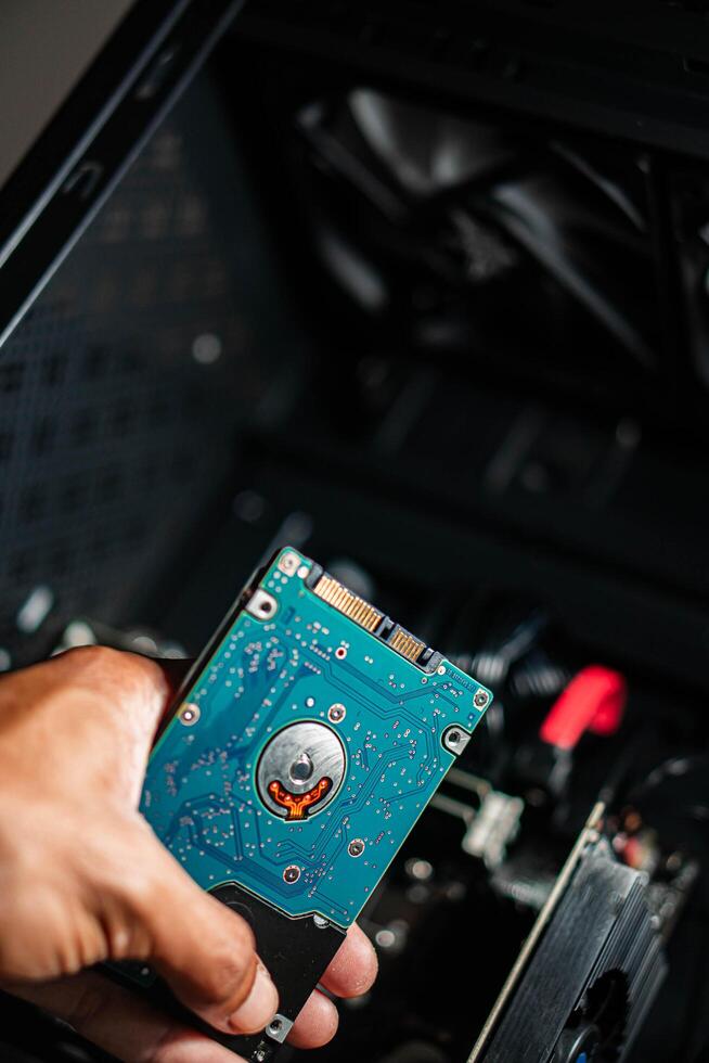 Person holding internal hard drive near computer case photo