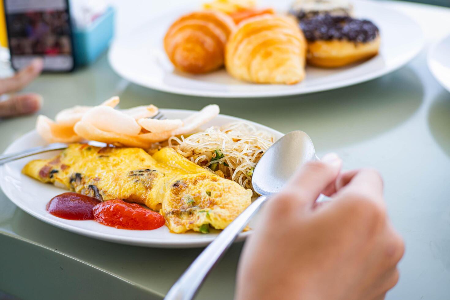 Breakfast plate with omelette, noodles, and pastries photo