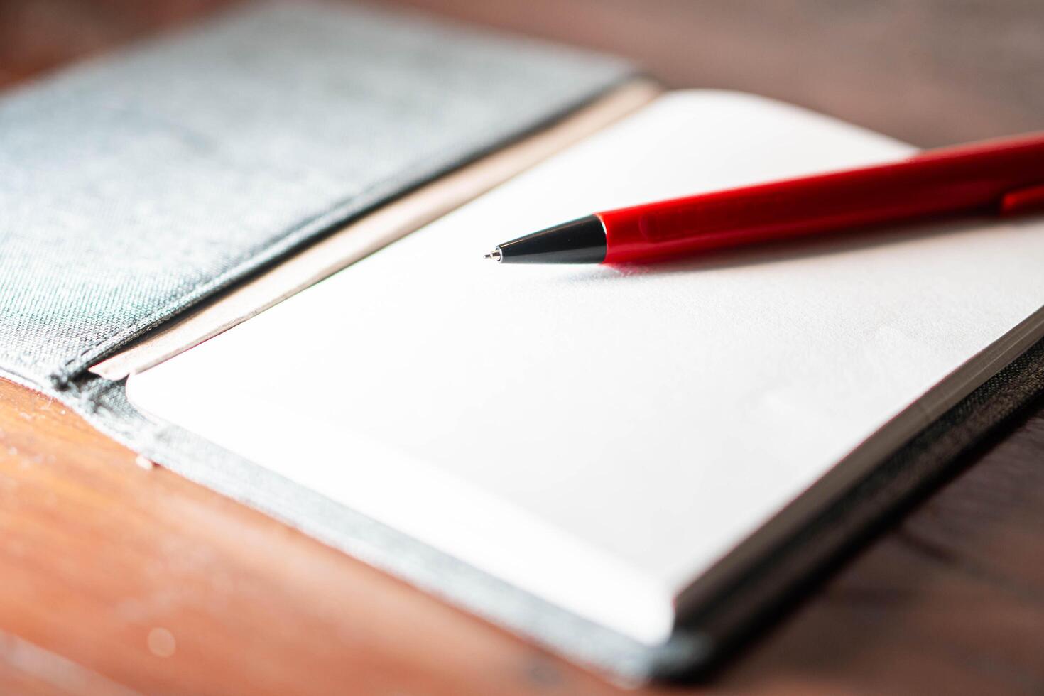 Open notebook with red pen on wooden surface photo