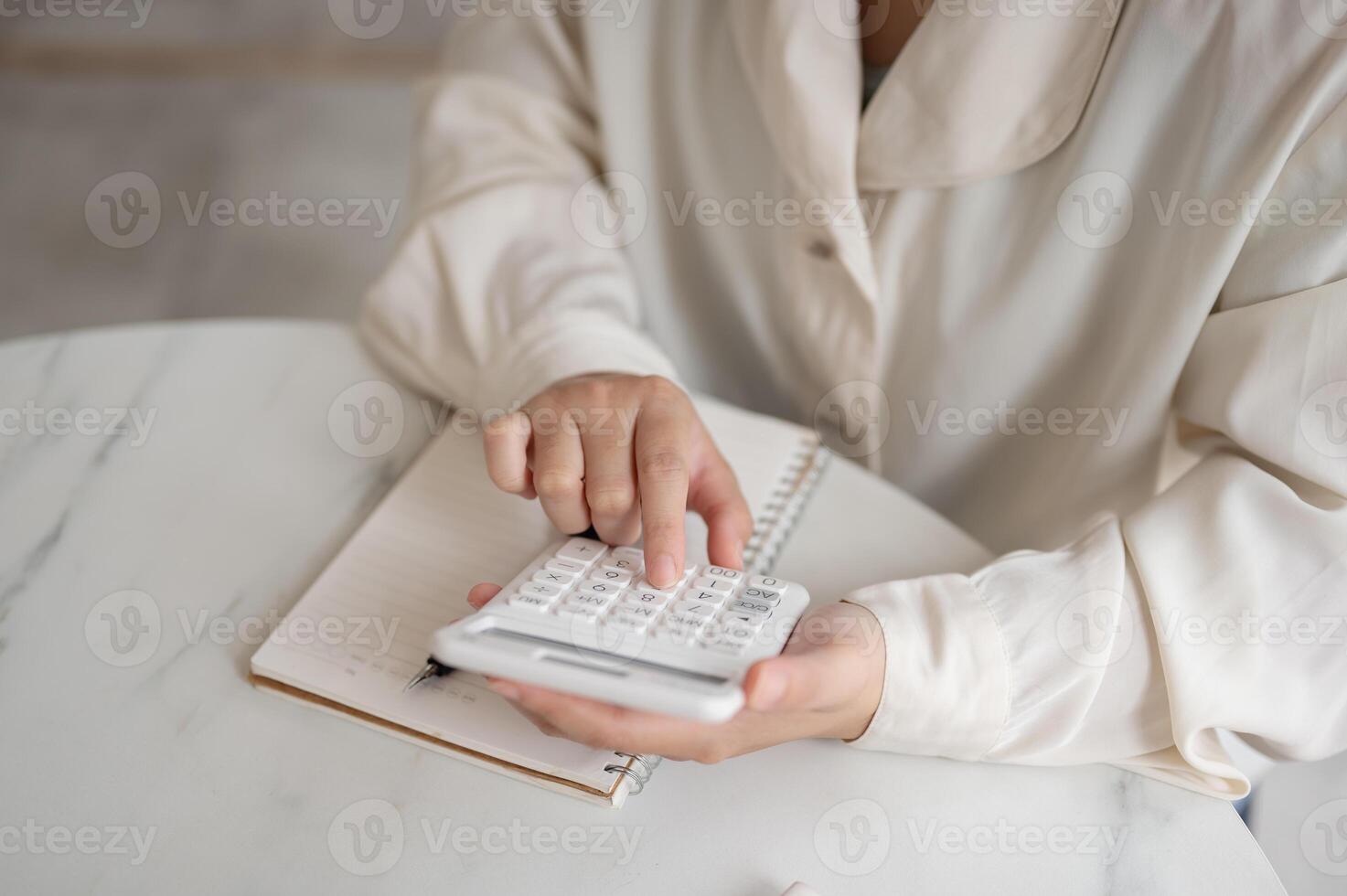 A close-up image of a woman using a calculator at a table, checking and calculating her budget. photo