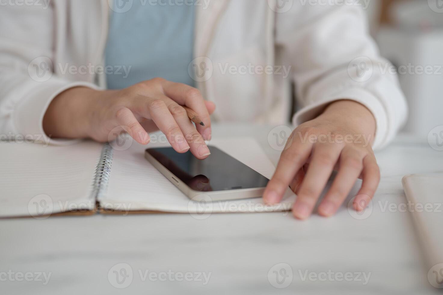 A close-up image of a woman in casual clothes is using her smartphone while working. photo