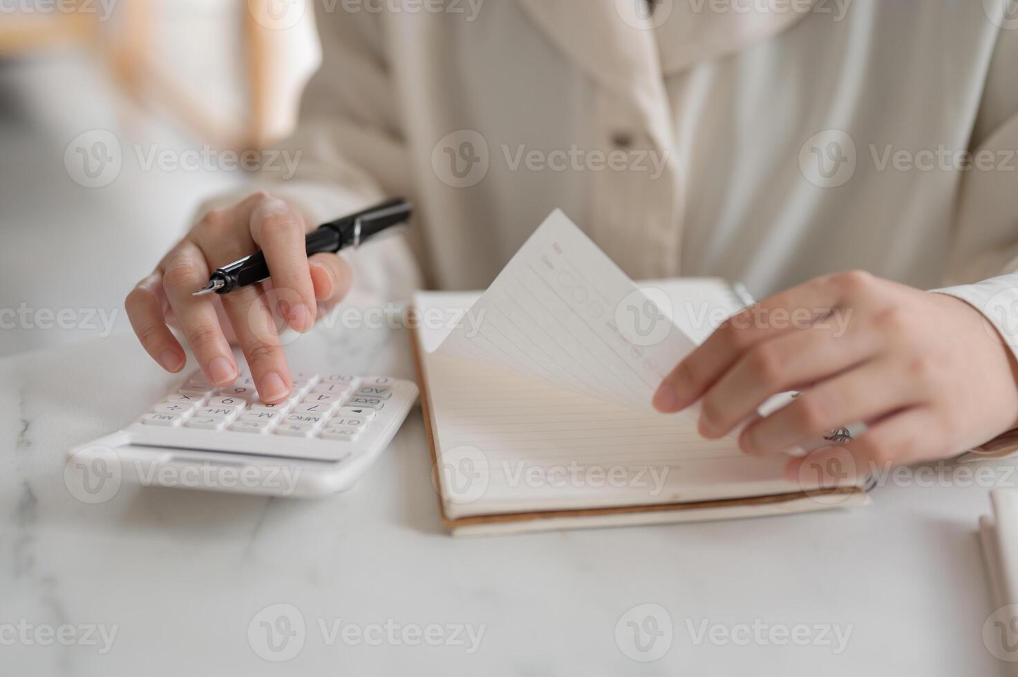 A close-up image of a woman using a calculator at a table, checking and calculating her budget. photo
