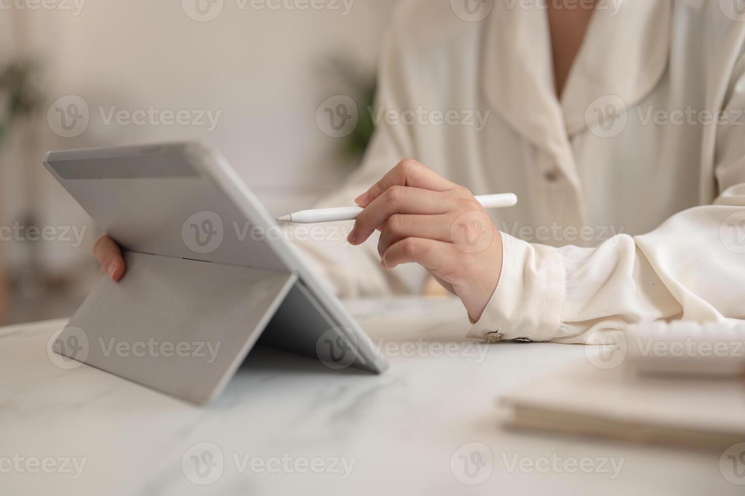A woman holding a stylus pen and using her digital tablet, working remotely from a cafe. photo